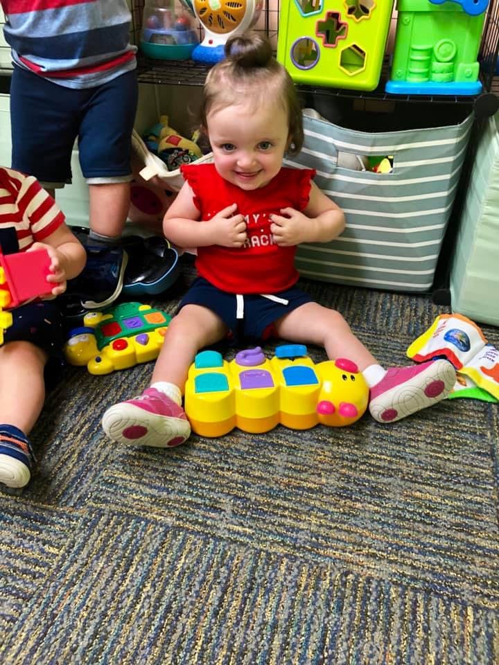 Child sitting on floor with a toy caterpillar