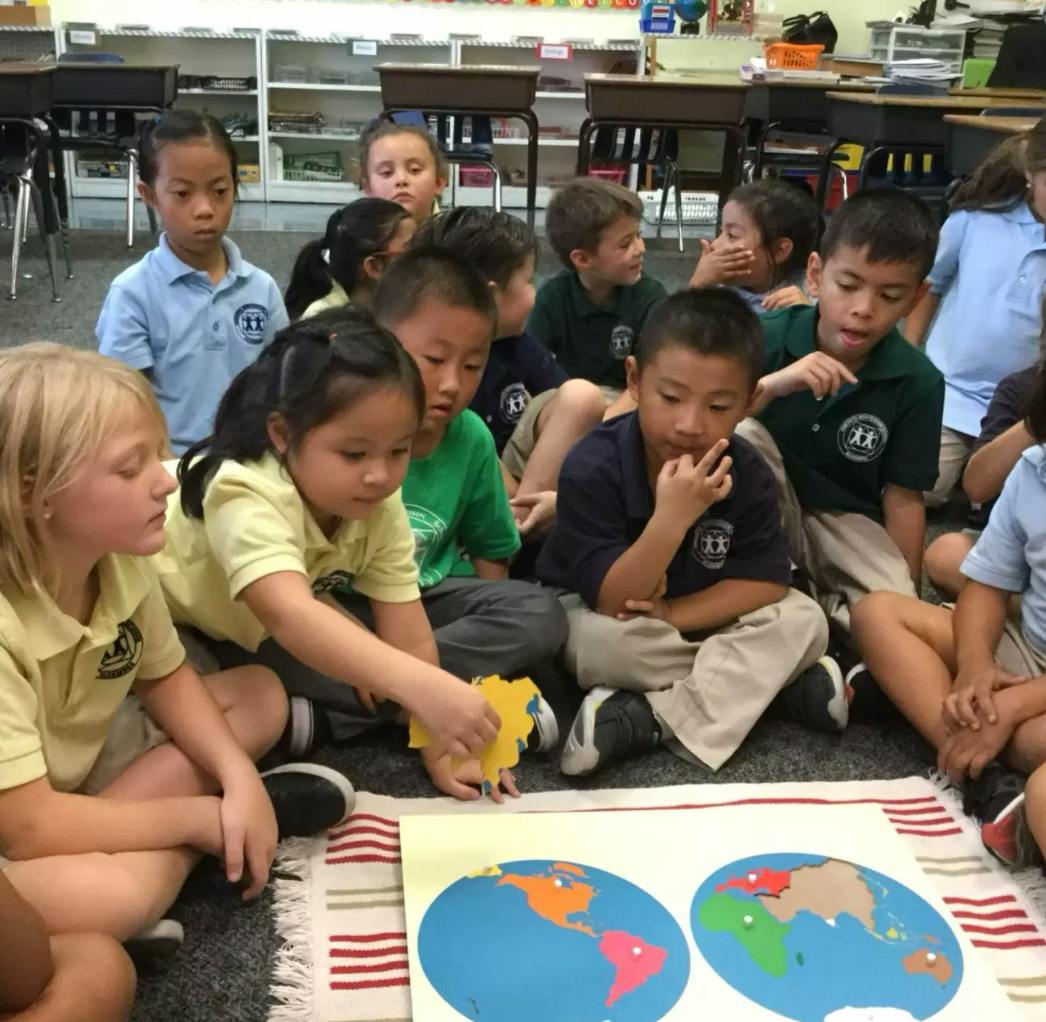 Children sitting on floor around a world map puzzle