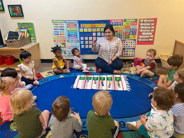 Adult and children sitting on a rug in a classroom