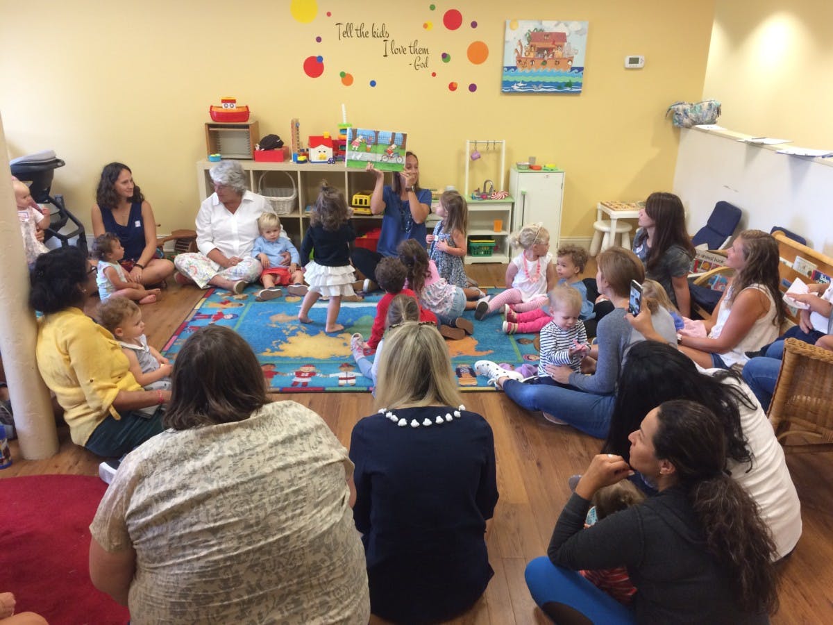 Adults and children sitting on the floor in a classroom
