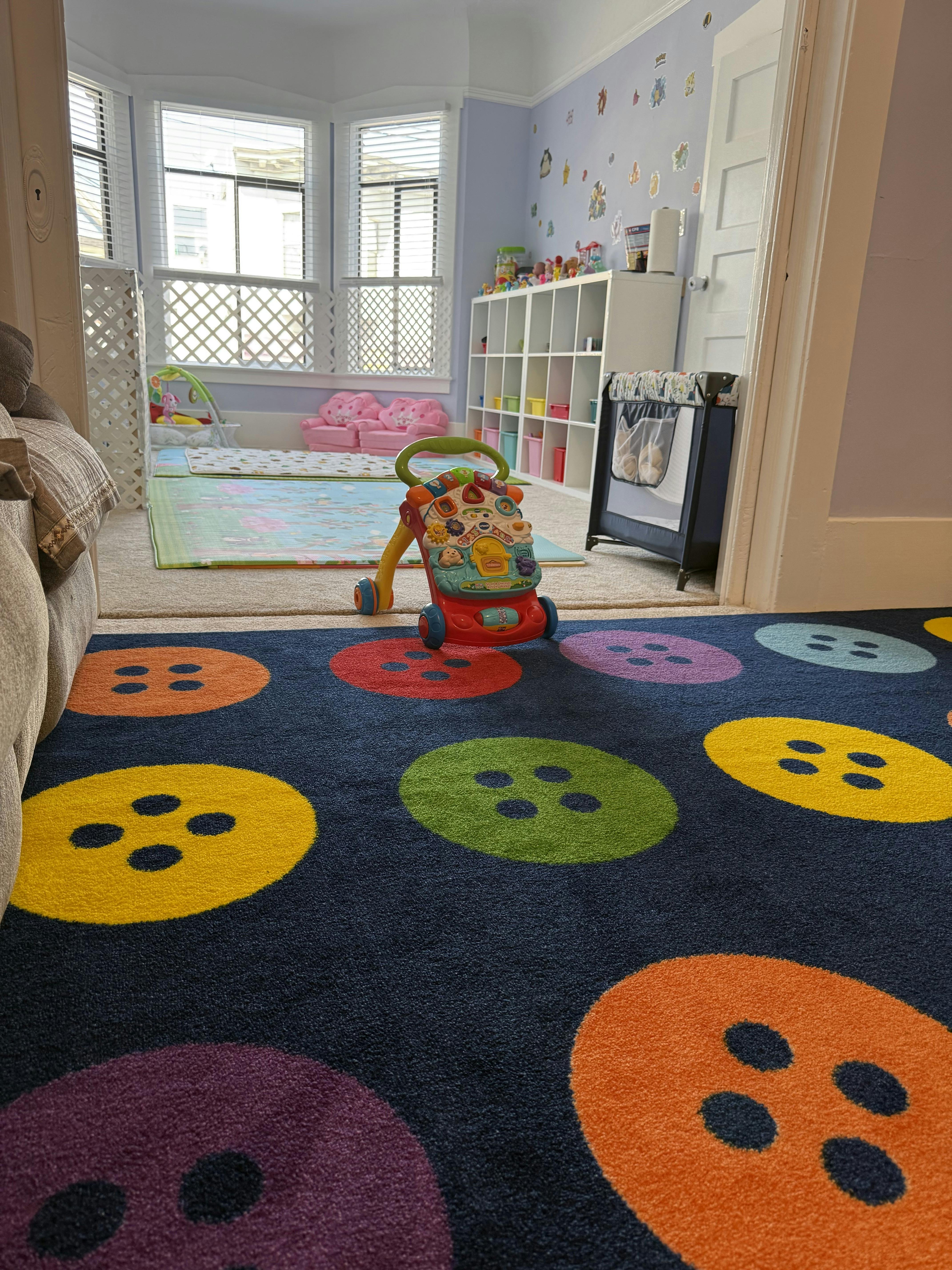 Colorful button-patterned rug in a child's room with a baby walker