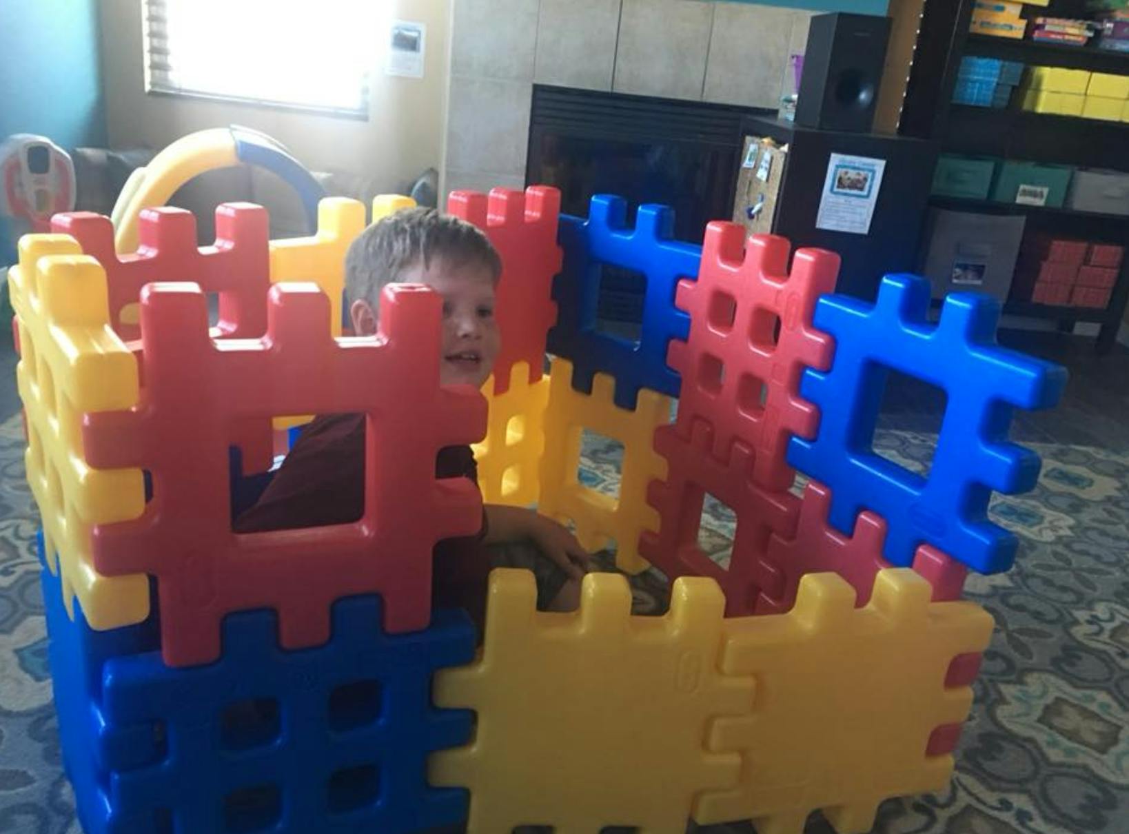 Child in a structure made of large colorful interlocking blocks