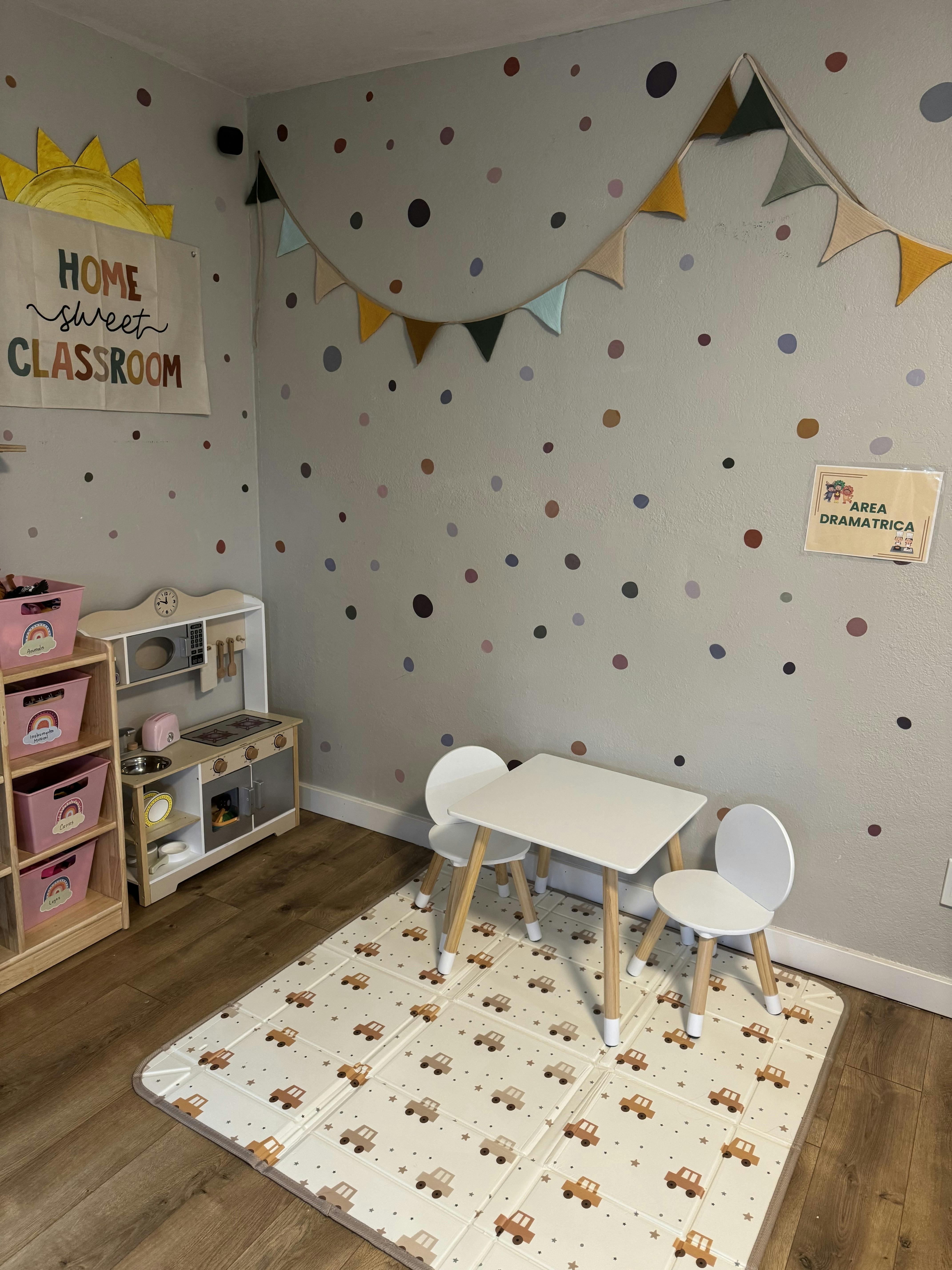 A classroom with a play kitchen, toy storage, and a small table with two chairs