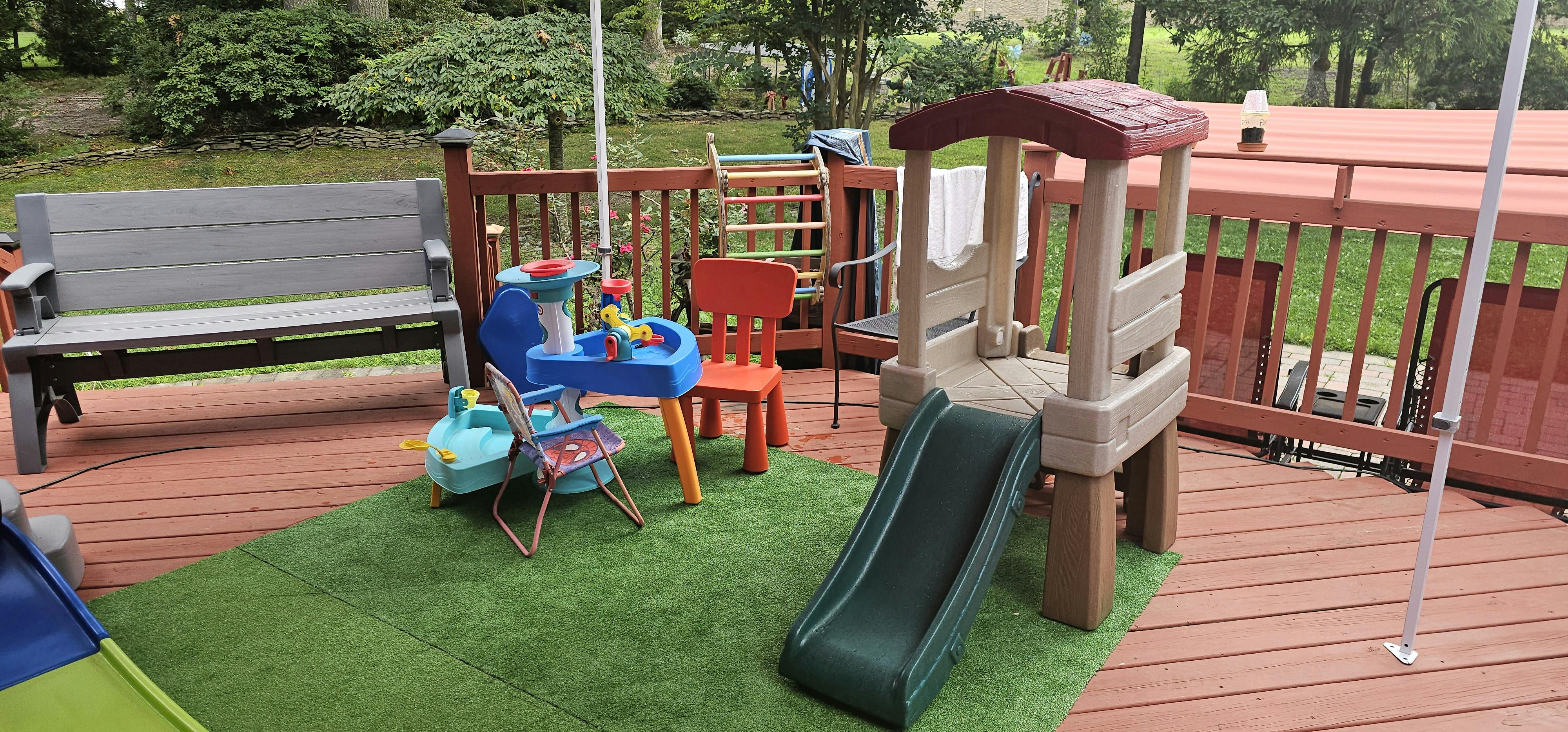 Playground equipment on a deck with artificial grass