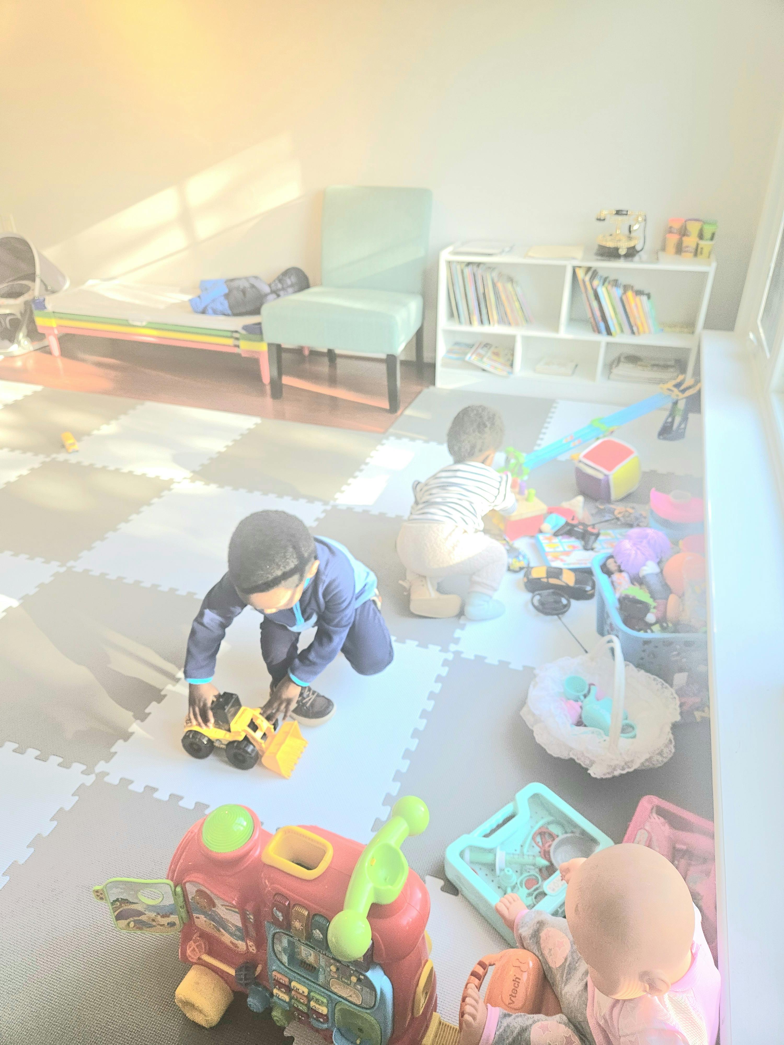 Two children playing with toys on a mat in a room