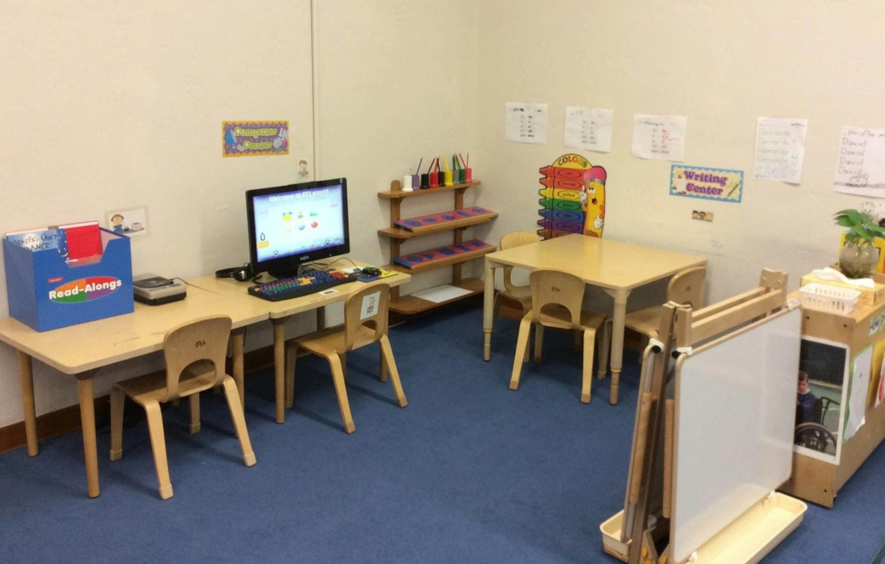Classroom with small tables, chairs, and a computer
