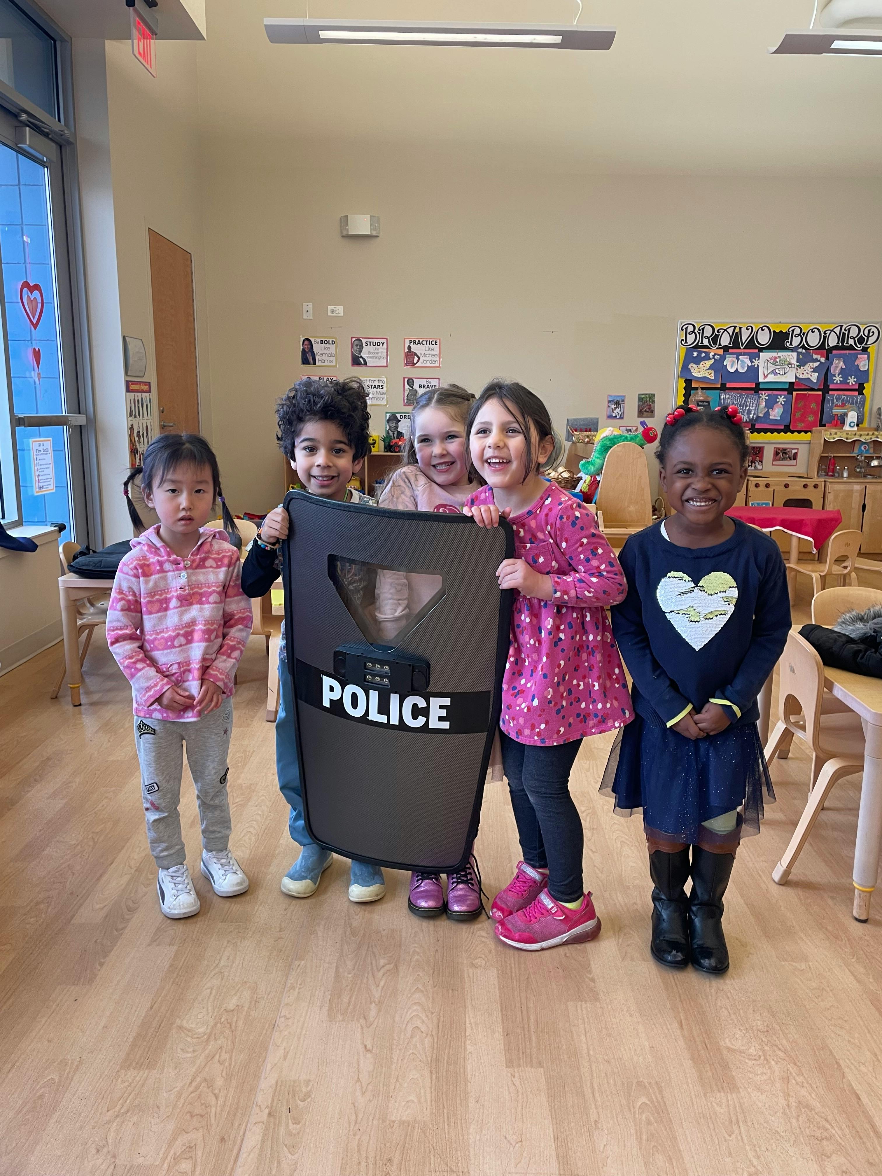 Four children holding a police shield in a classroom