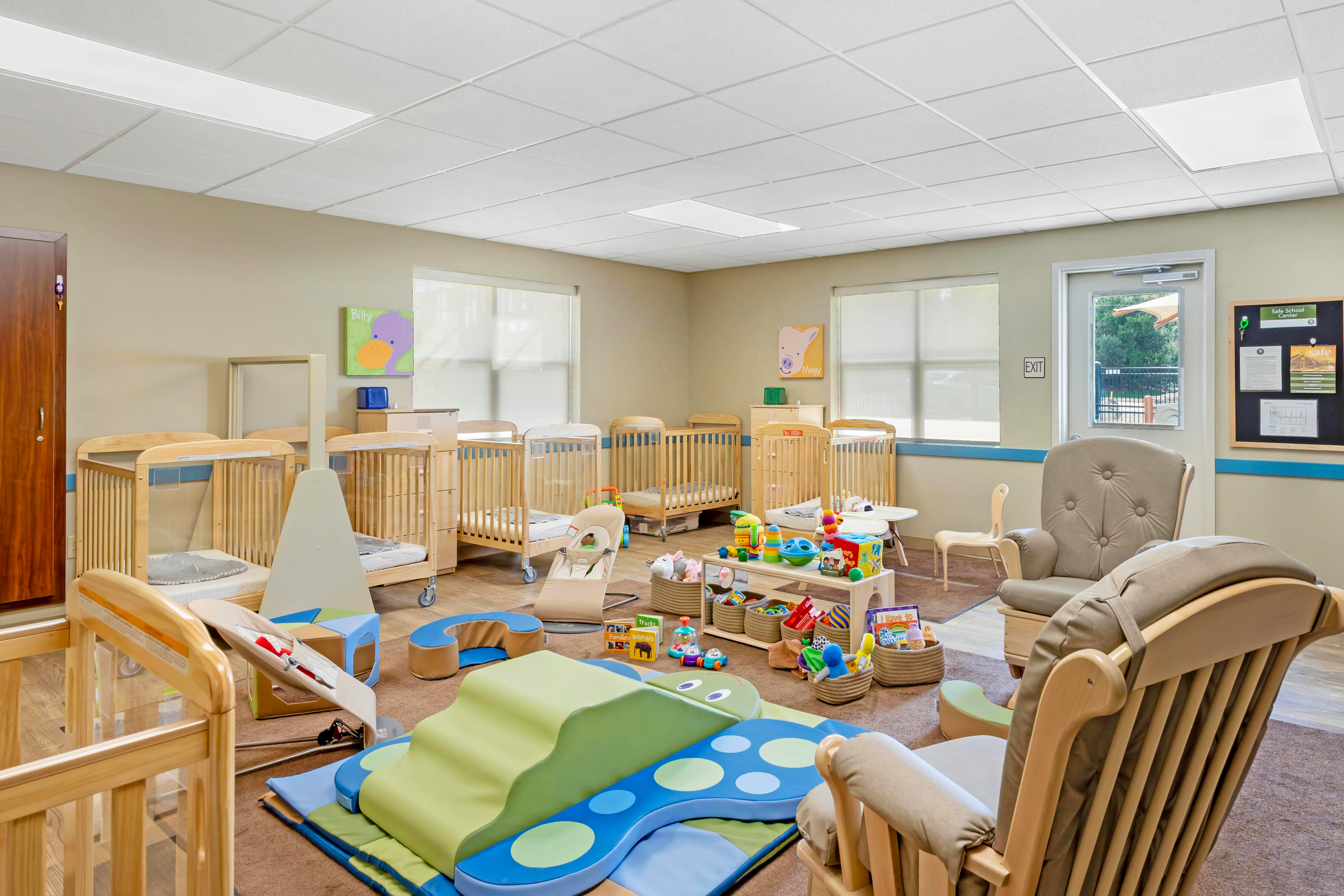 A daycare room with multiple cribs, a play mat, and various toys