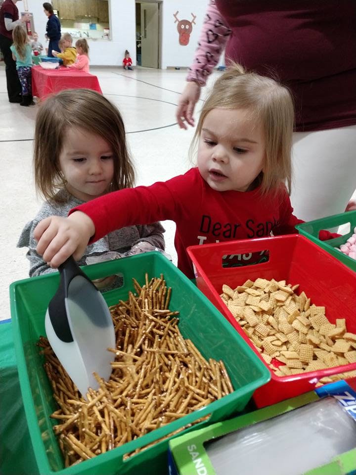 Two children scooping snacks from bins