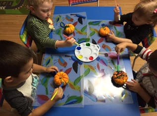 Children painting small pumpkins at a table