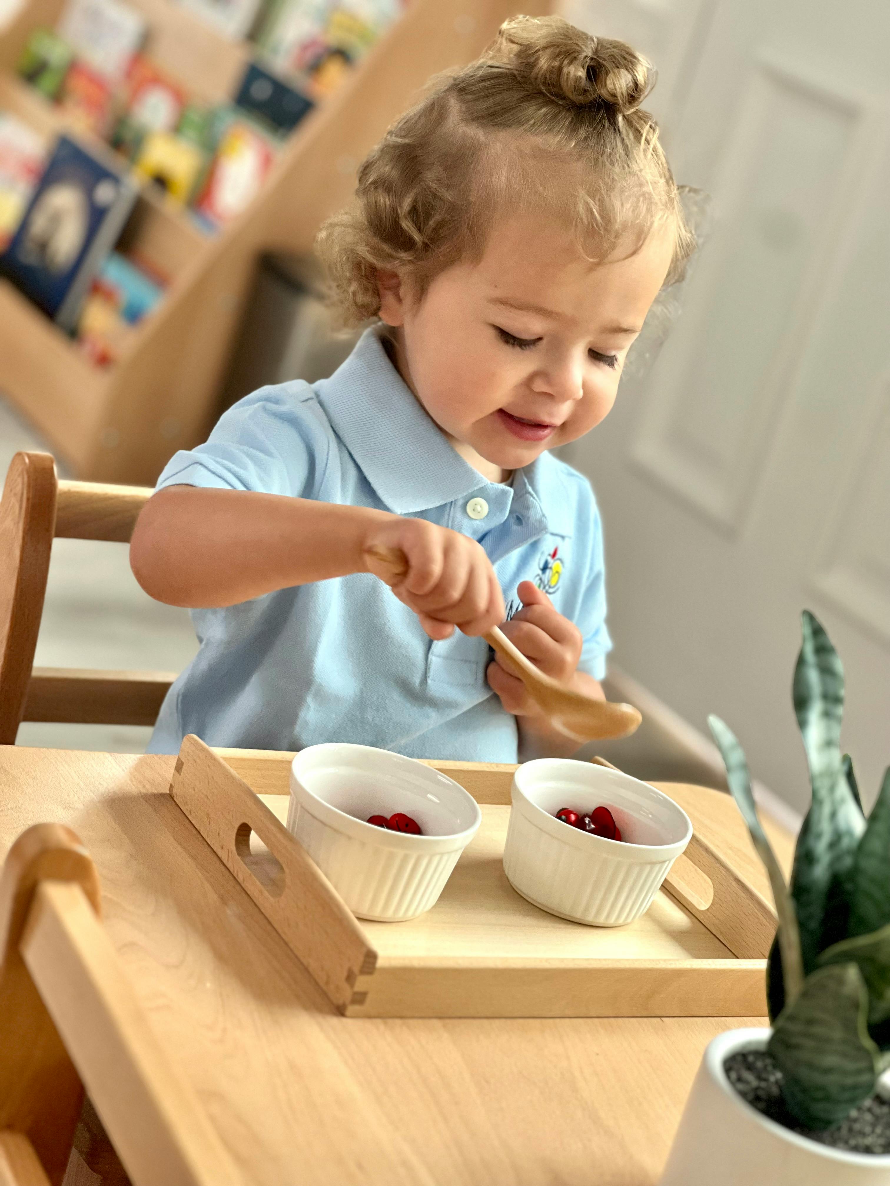 Child sitting at a table with two bowls of berries and a spoon