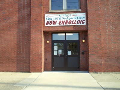 Building entrance with a "Now enrolling" sign above the door