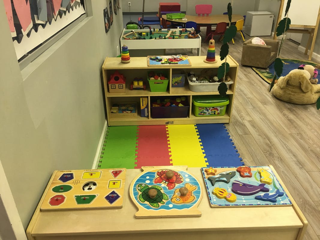 Children's play area with puzzles, shelves of toys, and colorful floor mats