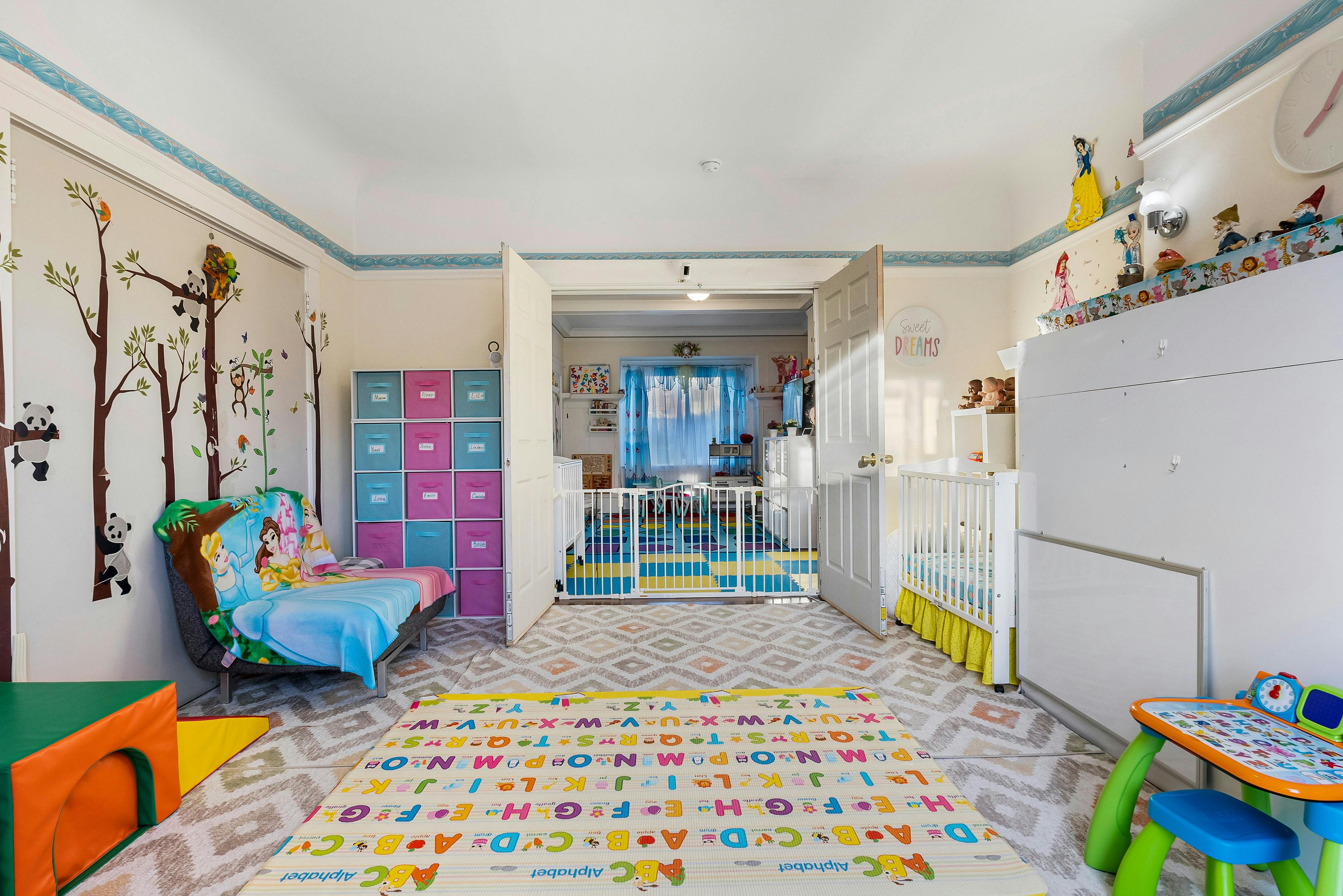 Playroom with a colorful alphabet rug and a crib behind a baby gate