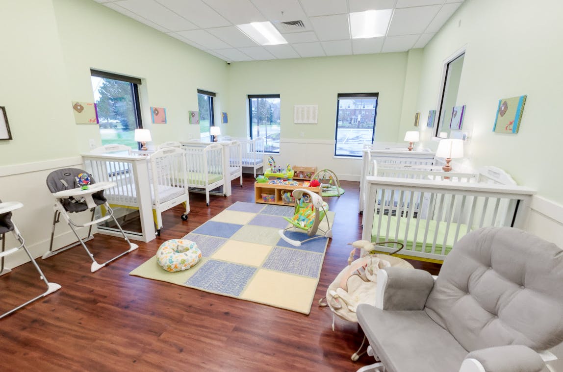 Room with multiple cribs, high chairs, and a checkered rug