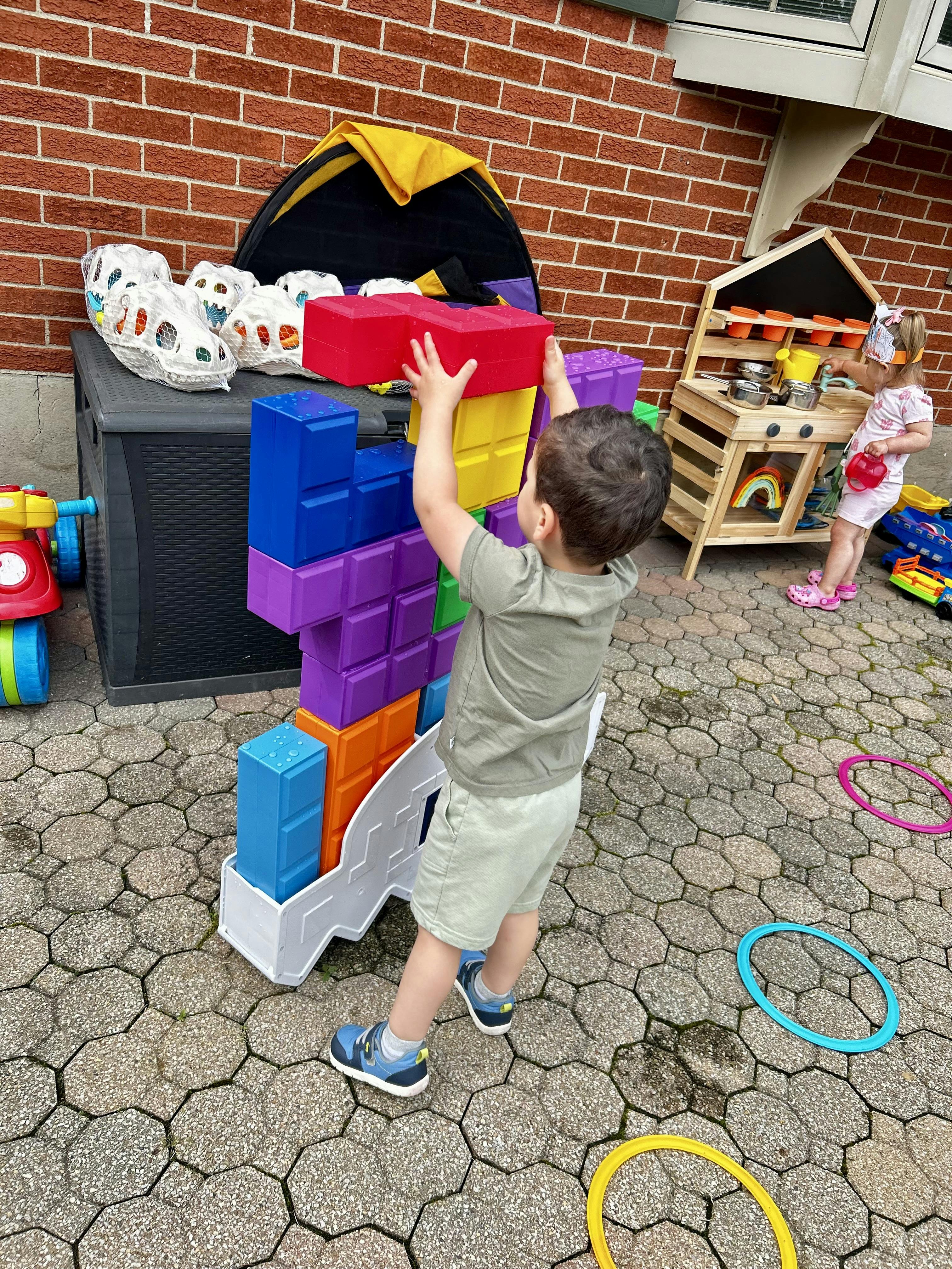 Child stacking large colorful blocks outdoors