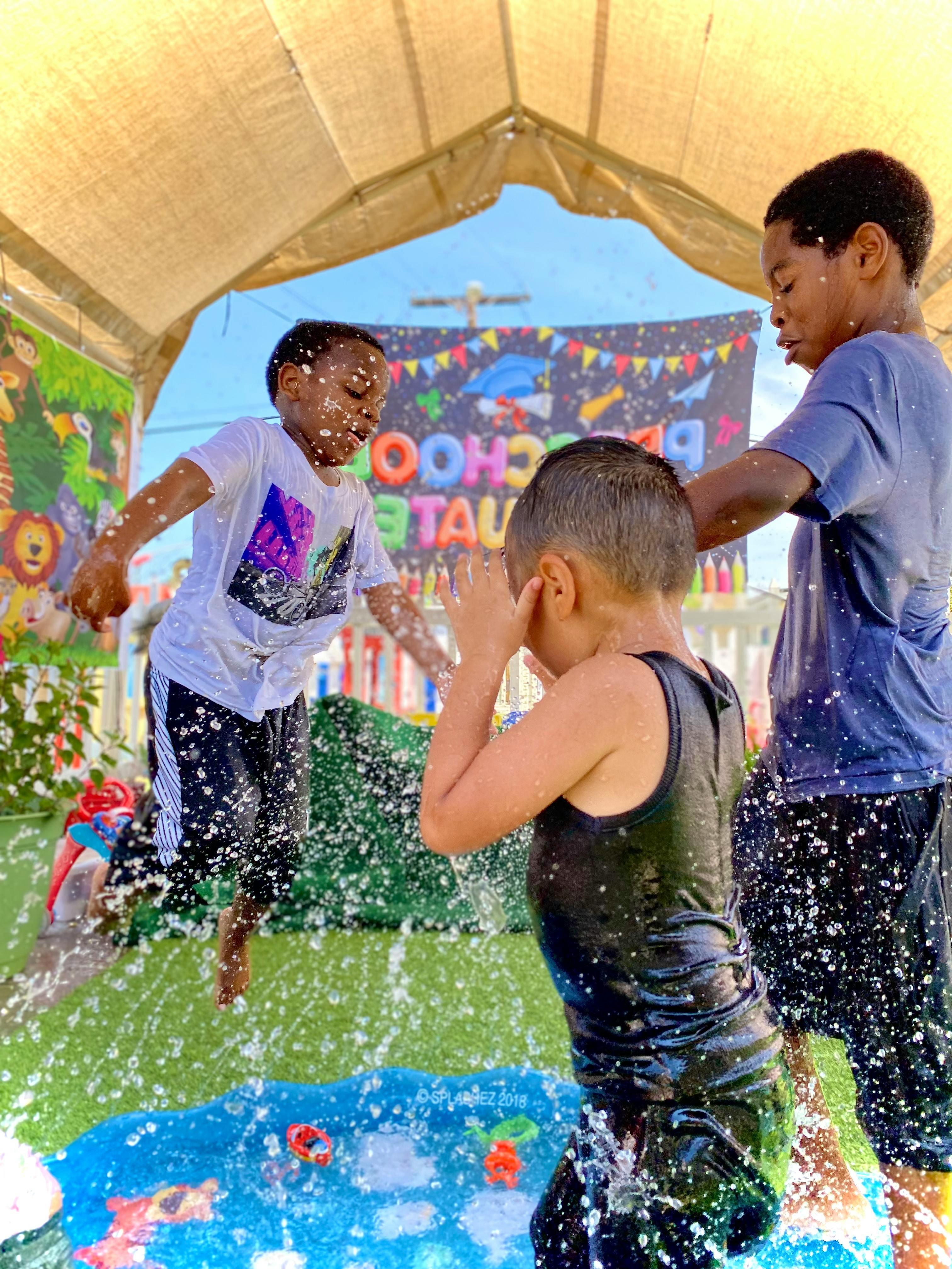 Three children playing in splashing water