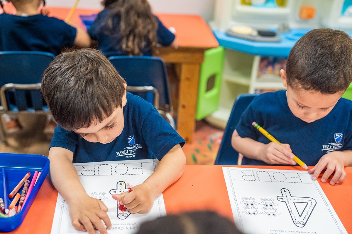 Two children coloring at a table in a classroom