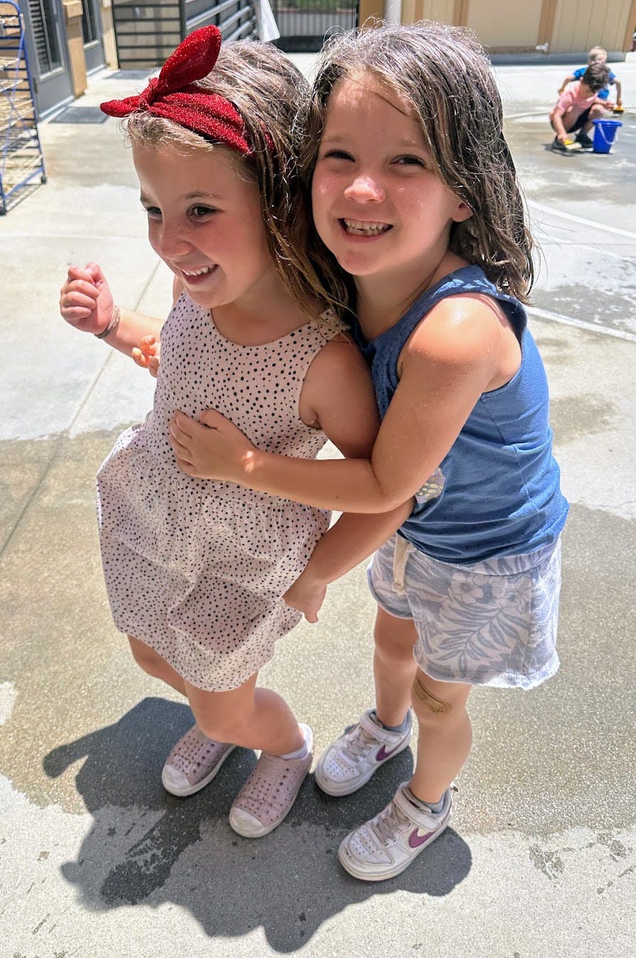 Two children hugging outdoors on a paved surface