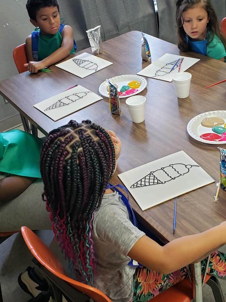 Children at a table with ice cream cone drawings and paint