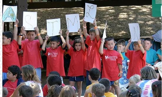 Children holding up signs with letters
