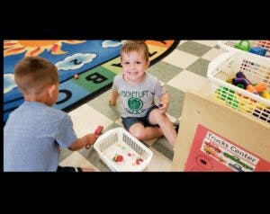 Two children playing with toys on a rug