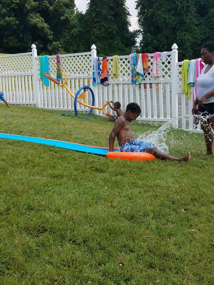 Child on a water slide in a grassy yard