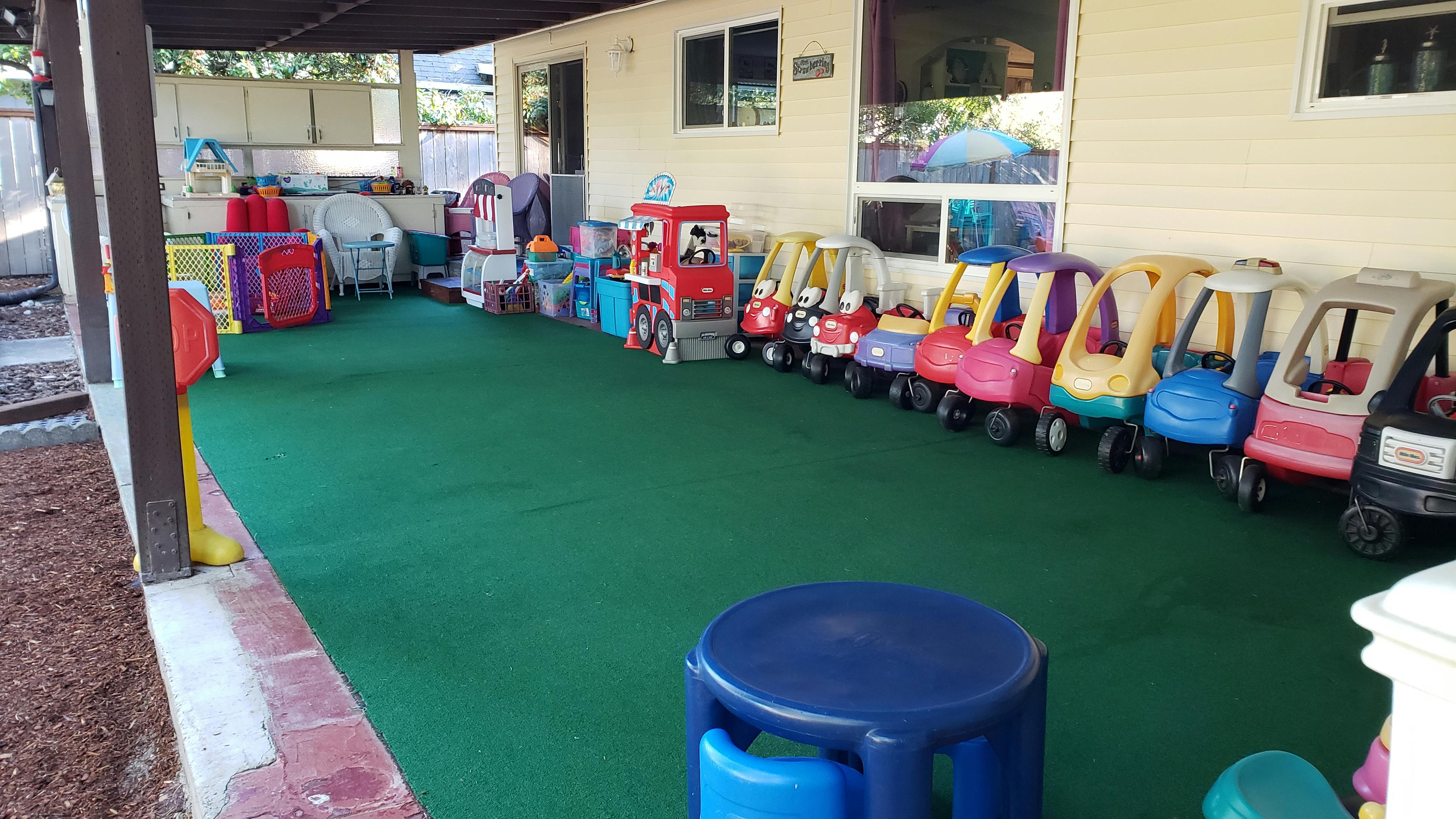 Outdoor play area with green turf and children's ride-on toys