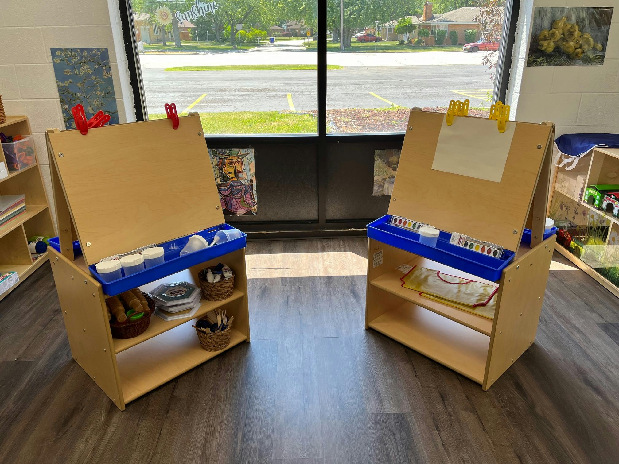Two wooden easels with blue trays in a classroom
