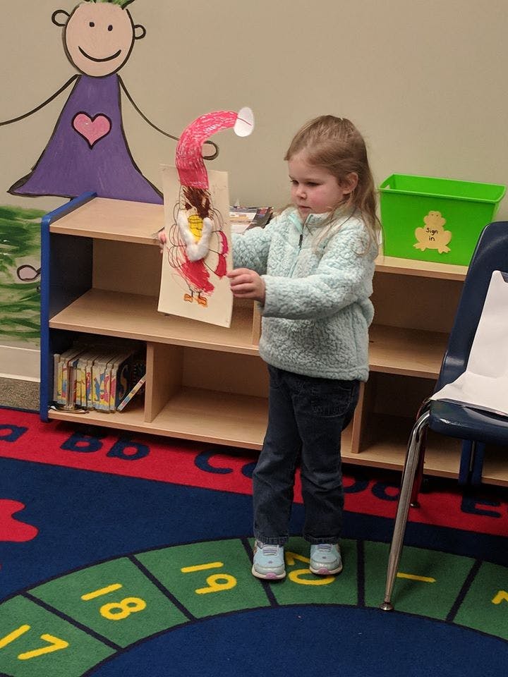 Child holding up a paper craft of a turkey
