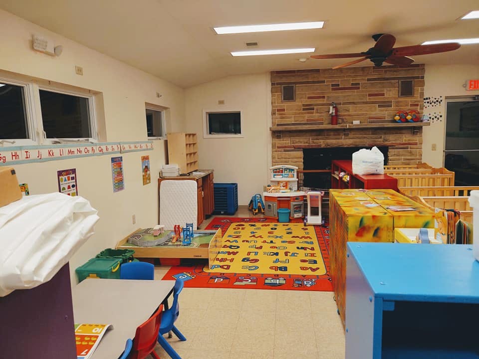 Playroom with colorful rugs, small tables, and a fireplace
