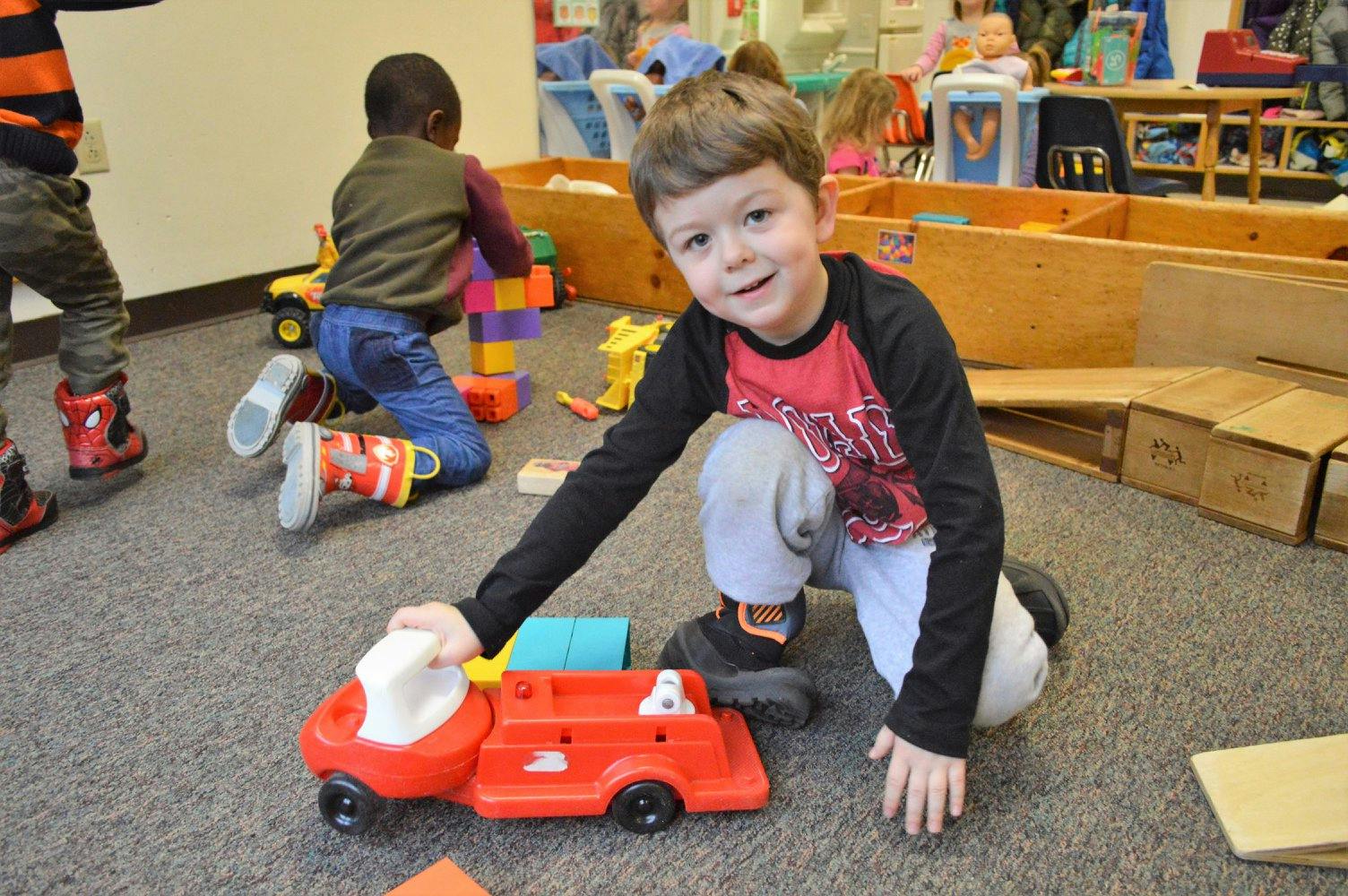Child playing with a toy fire truck on the floor