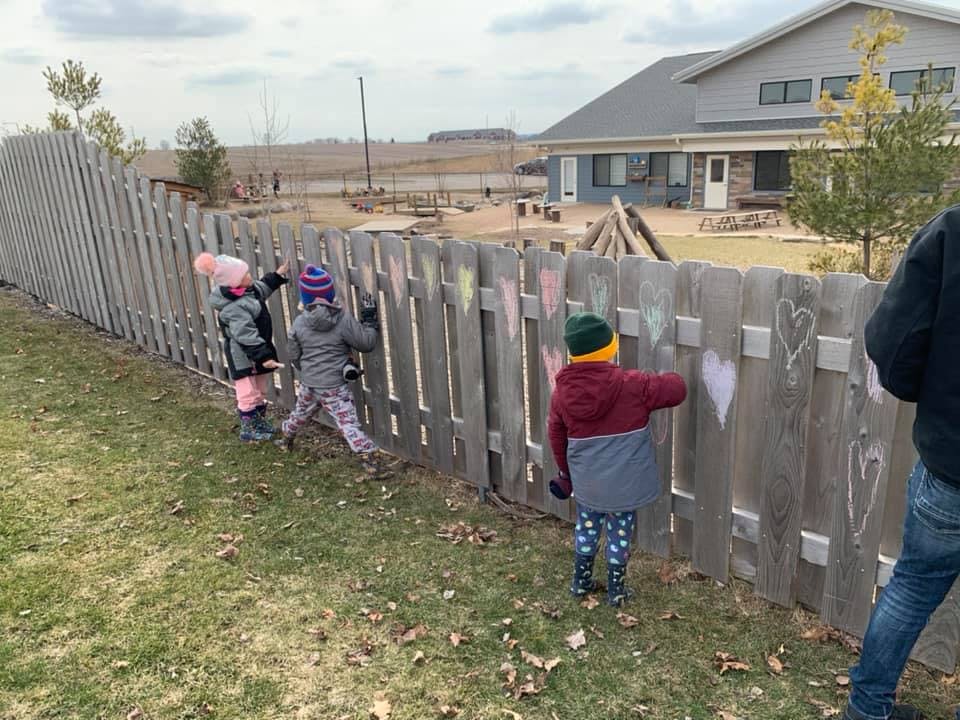 Children drawing on a wooden fence with chalk