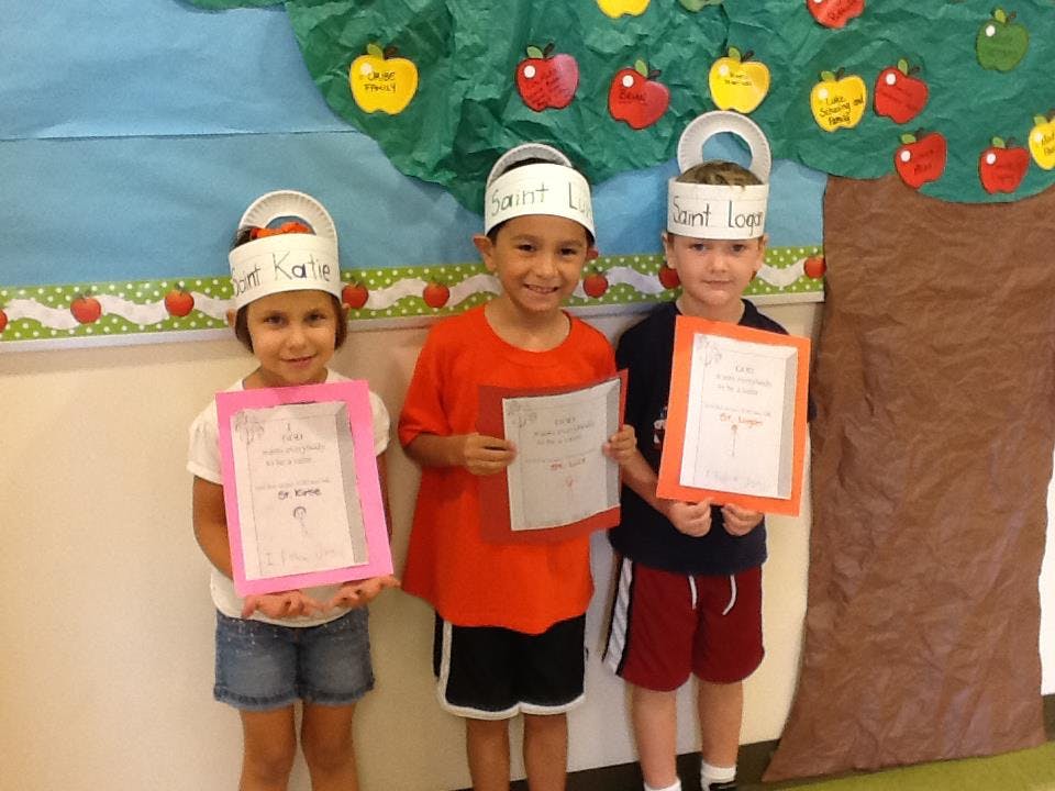 Three children wearing paper crowns and holding papers