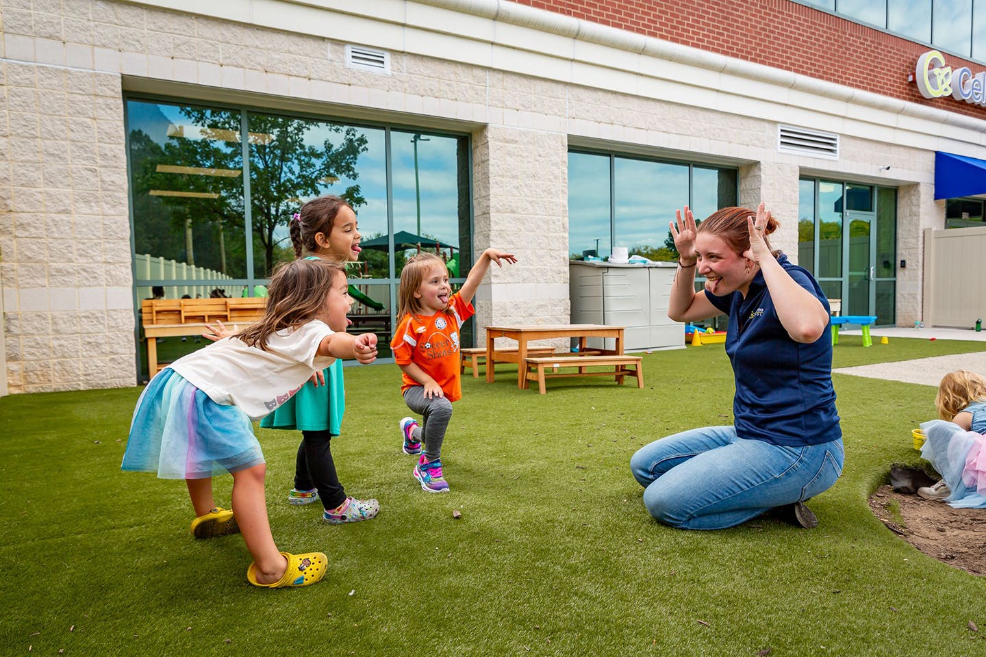 Adult and three children playing on artificial grass