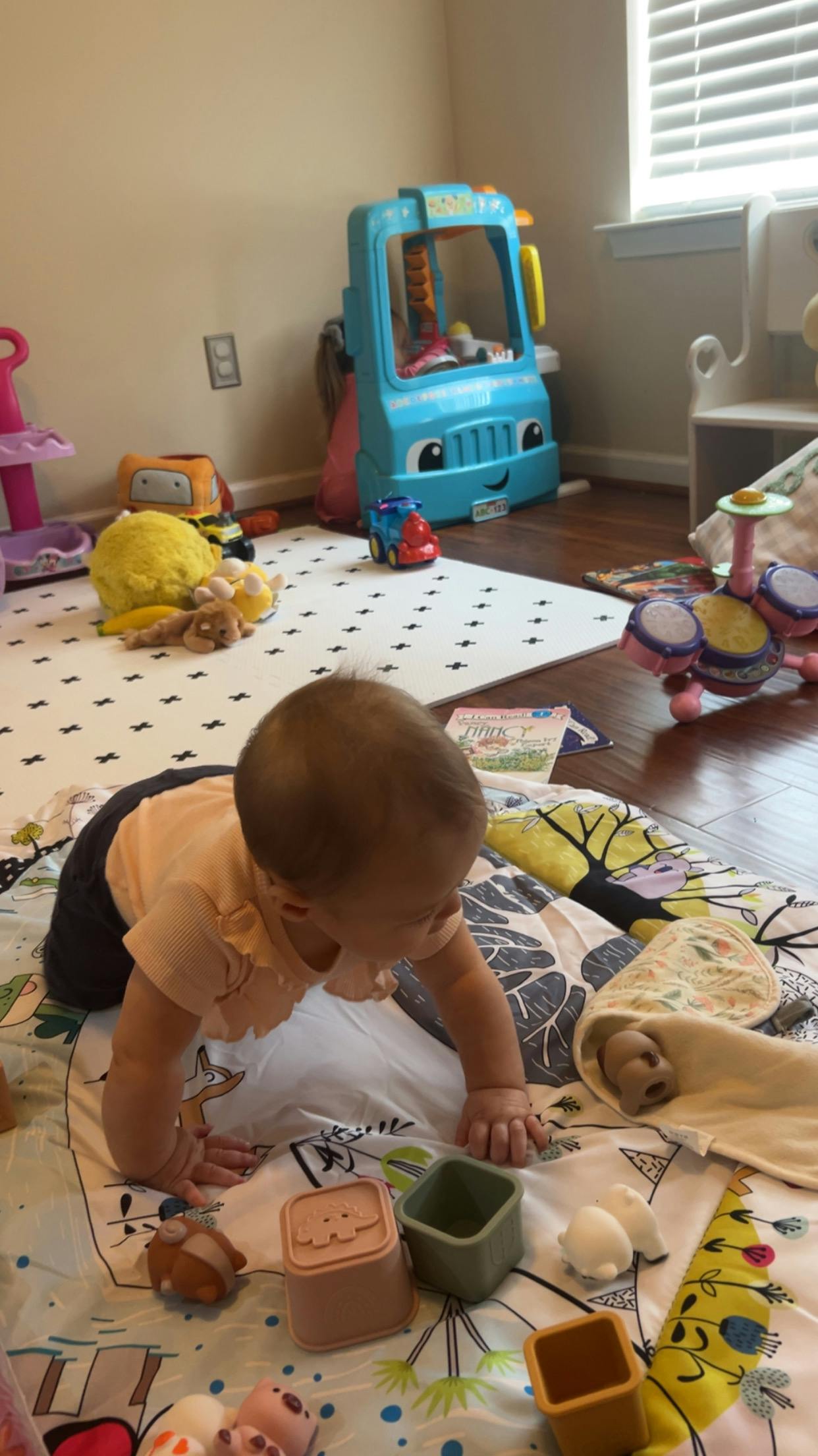 A child crawling on a play mat with various toys