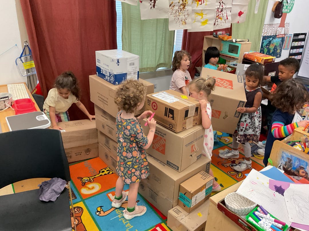 Children playing with cardboard boxes in a room