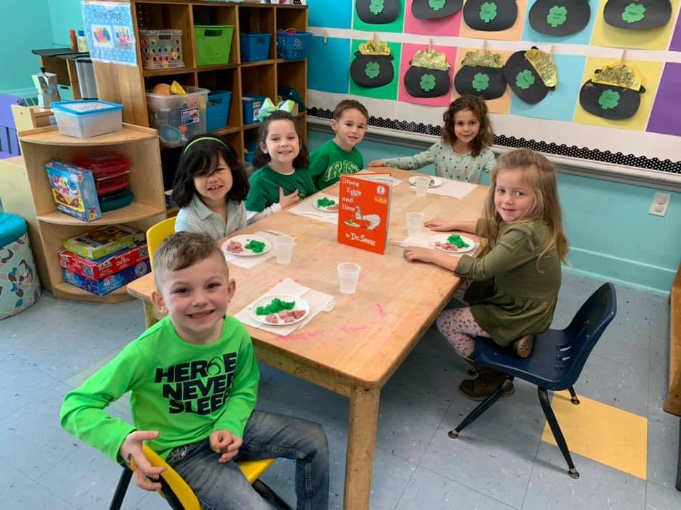 Six children sitting around a table in a classroom