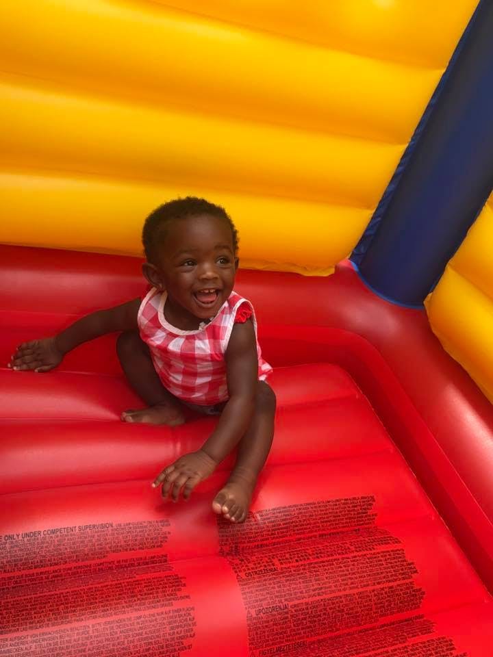 Child in a red and white checkered shirt sitting in a bouncy house
