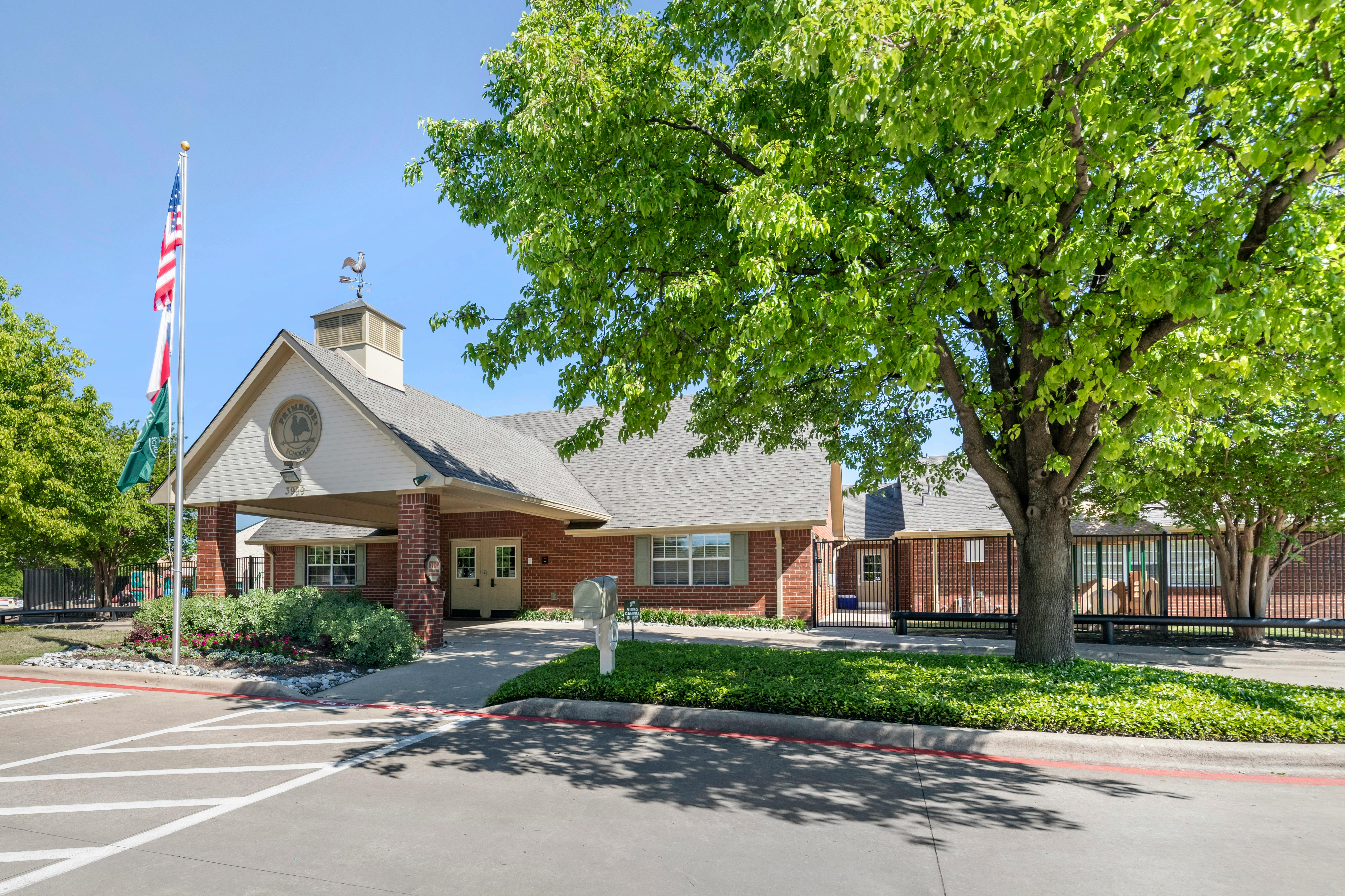 Brick building with a white entrance, flagpole, and green trees