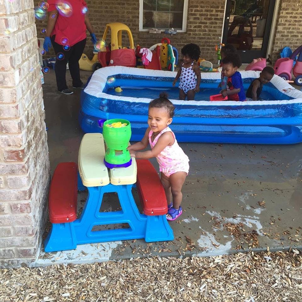 Child standing next to a toy picnic table with a bubble machine
