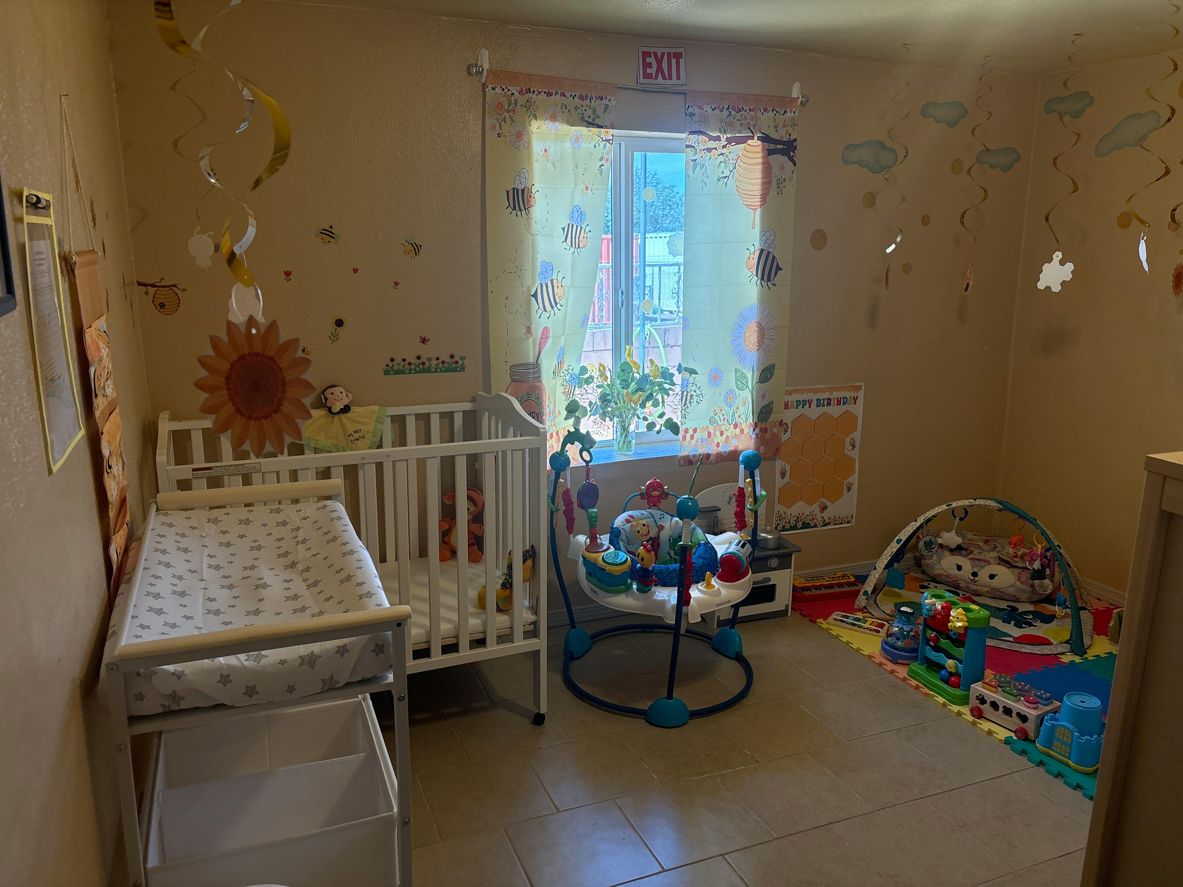 Childcare room with a crib, changing table, activity jumper, and play area