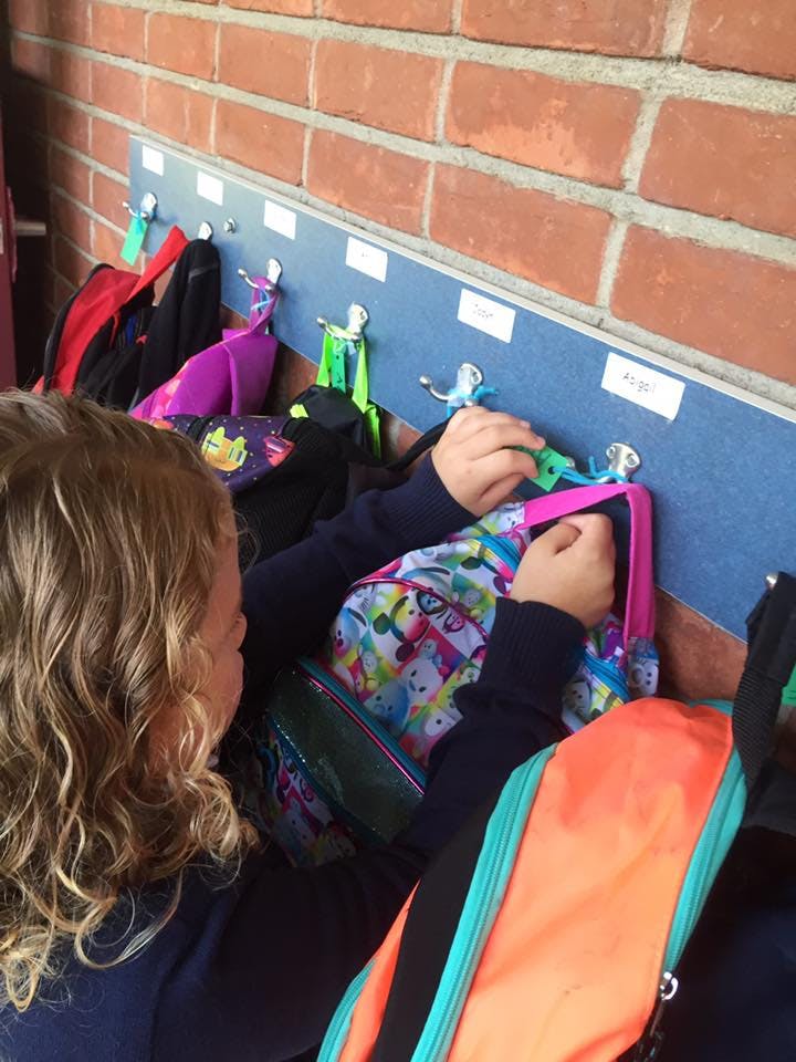 Child hanging a backpack on a hook