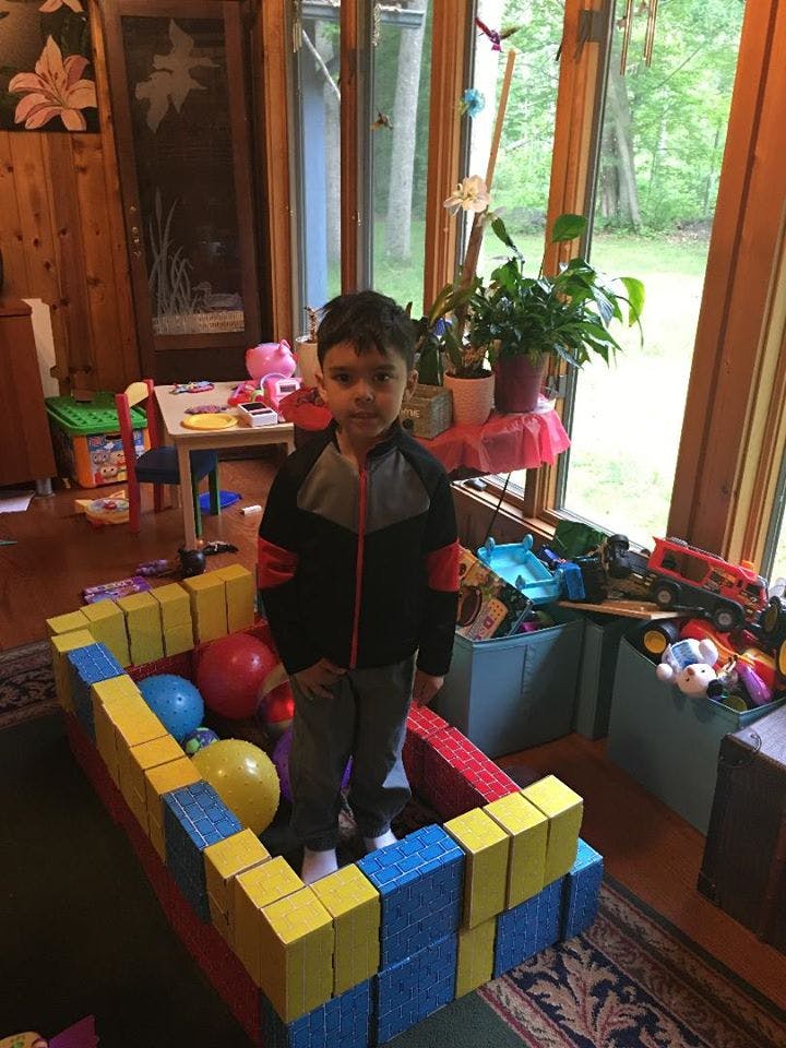 Child standing inside a structure made of large building blocks