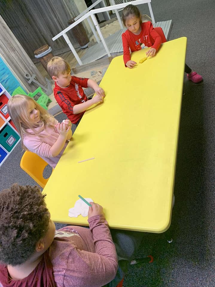 Children at a yellow table playing with modeling clay