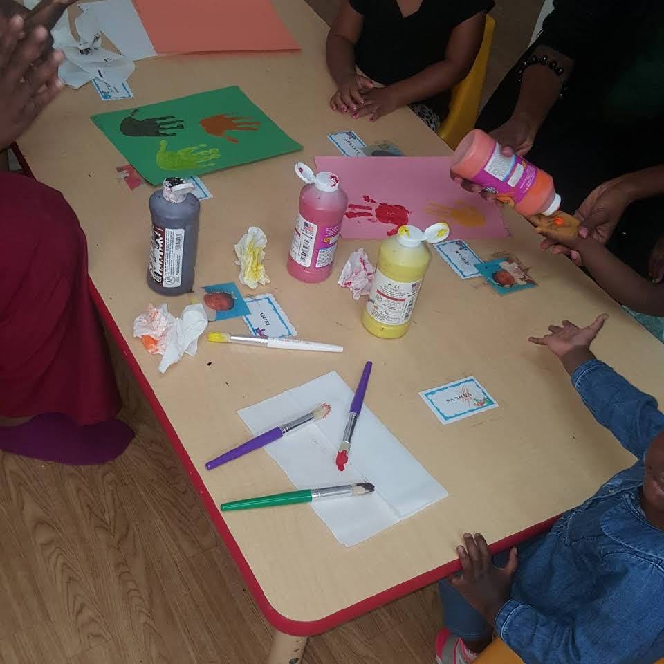 People painting handprints on paper at a table