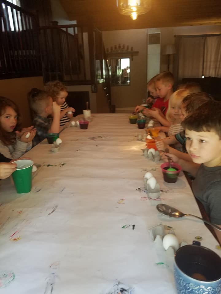 Children sitting at a long table decorating eggs