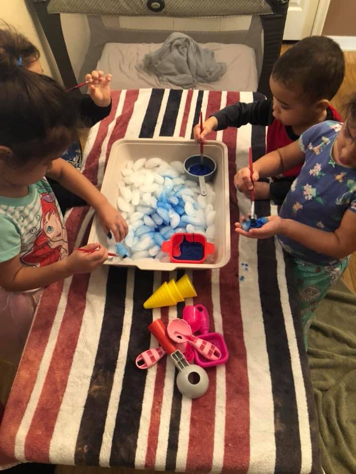 Children playing with ice and blue liquid in a sensory bin