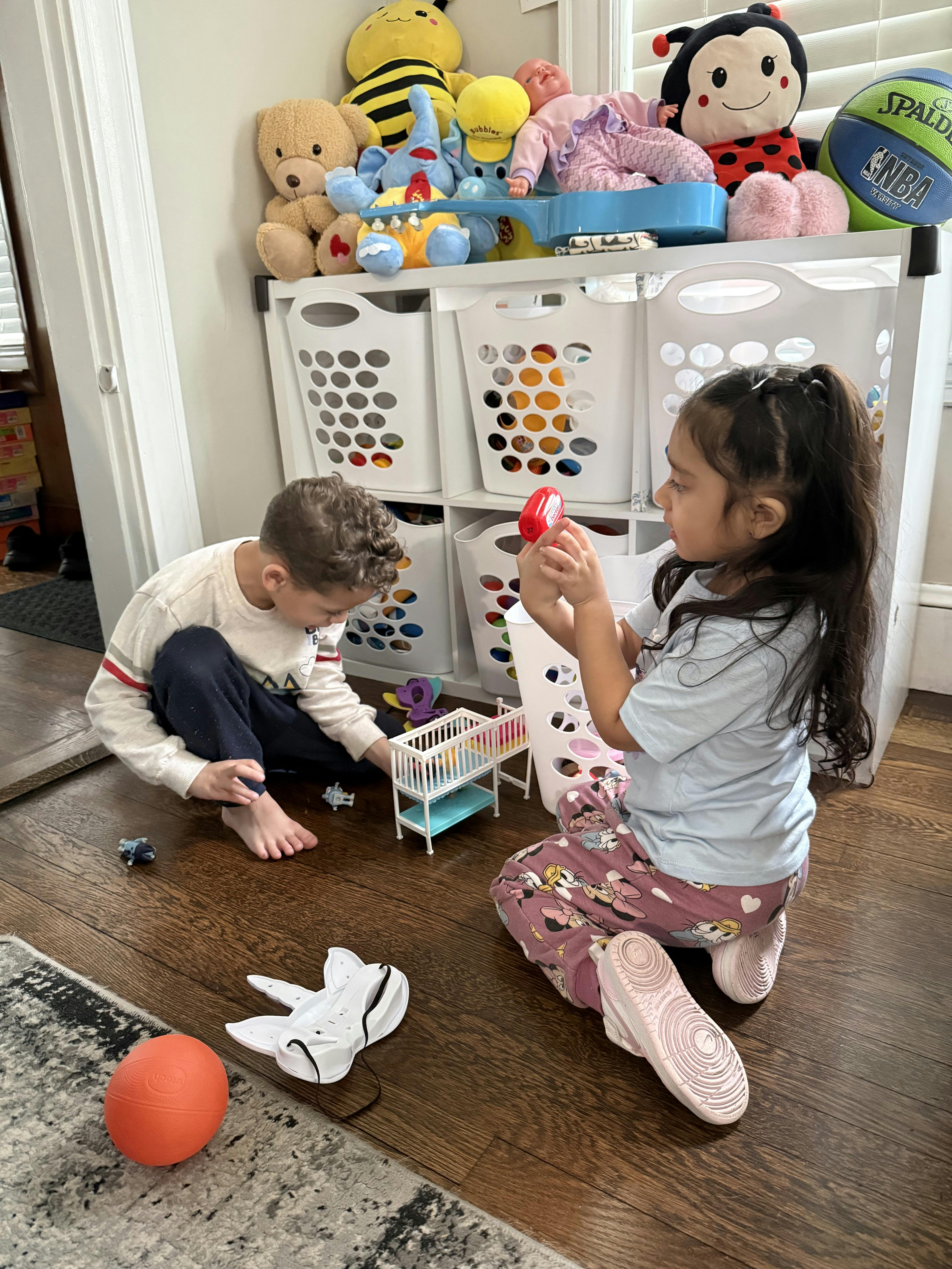 Two children playing with small toys on a playroom floor