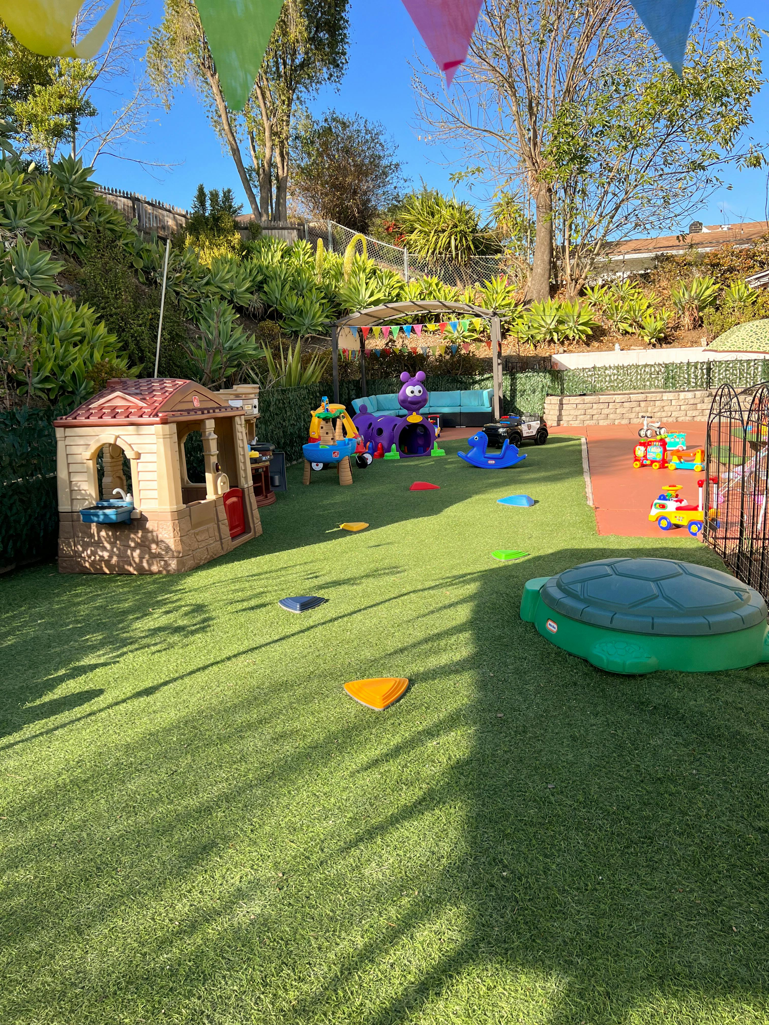 Outdoor play area with playhouse, toys, and a turtle sandbox